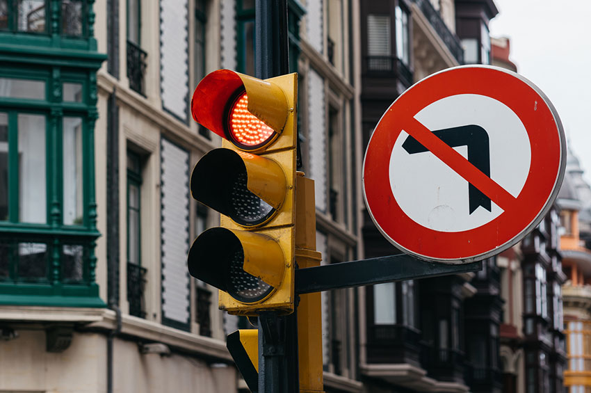 Traffic light with red and yellow signals above a no left turn sign on an urban street, symbolizing dangerous left-turn crashes involving motorcycles in Georgia.